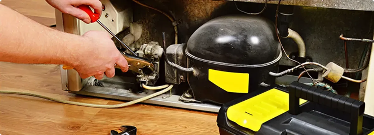 Refrigerator repair technician fixing the compressor and wiring in Rocky River, OH