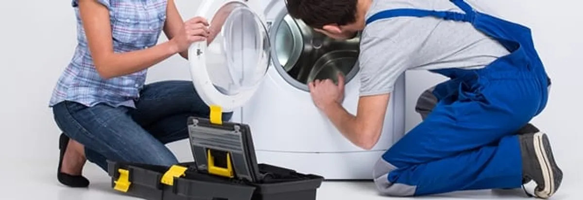 Washer repair technician inspecting a front-load washing machine with tools in Cleveland, OH