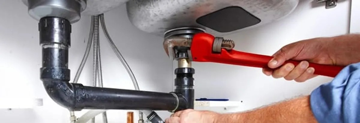 Garbage disposal repair technician tightening the sink drain and disposal connection in Cleveland, OH
