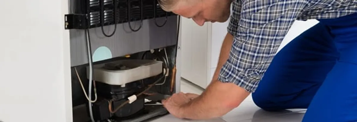 Refrigerator repair technician servicing the compressor and condenser area in Cleveland, OH